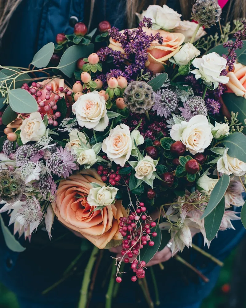 Lys og innbydende blomsterbutikk med sesongblomster i sink- og keramikkvaser